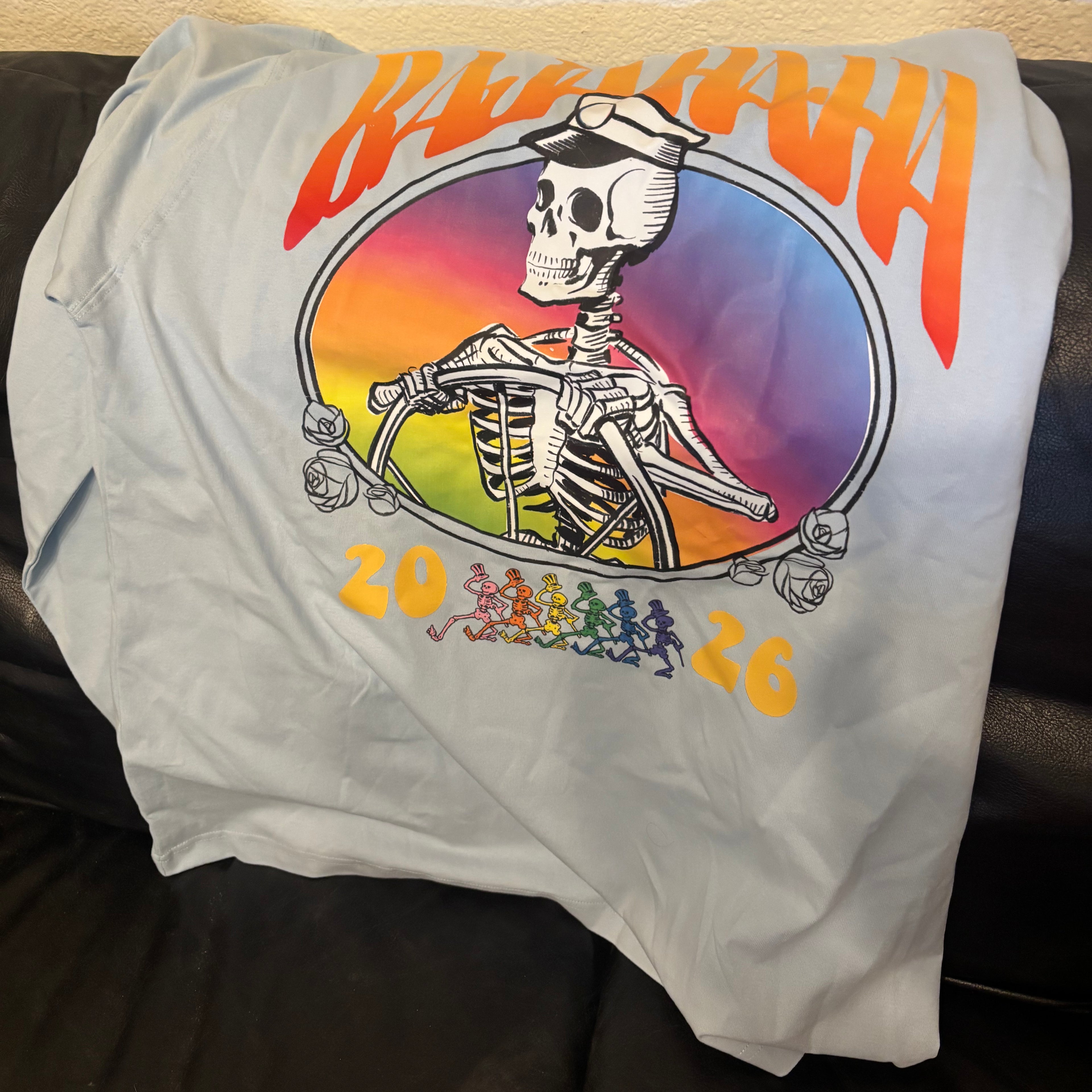 The back of a grey shirt with a skeleton captain and the words Baja Haha 2026. There is a sunset background to the skeleton.