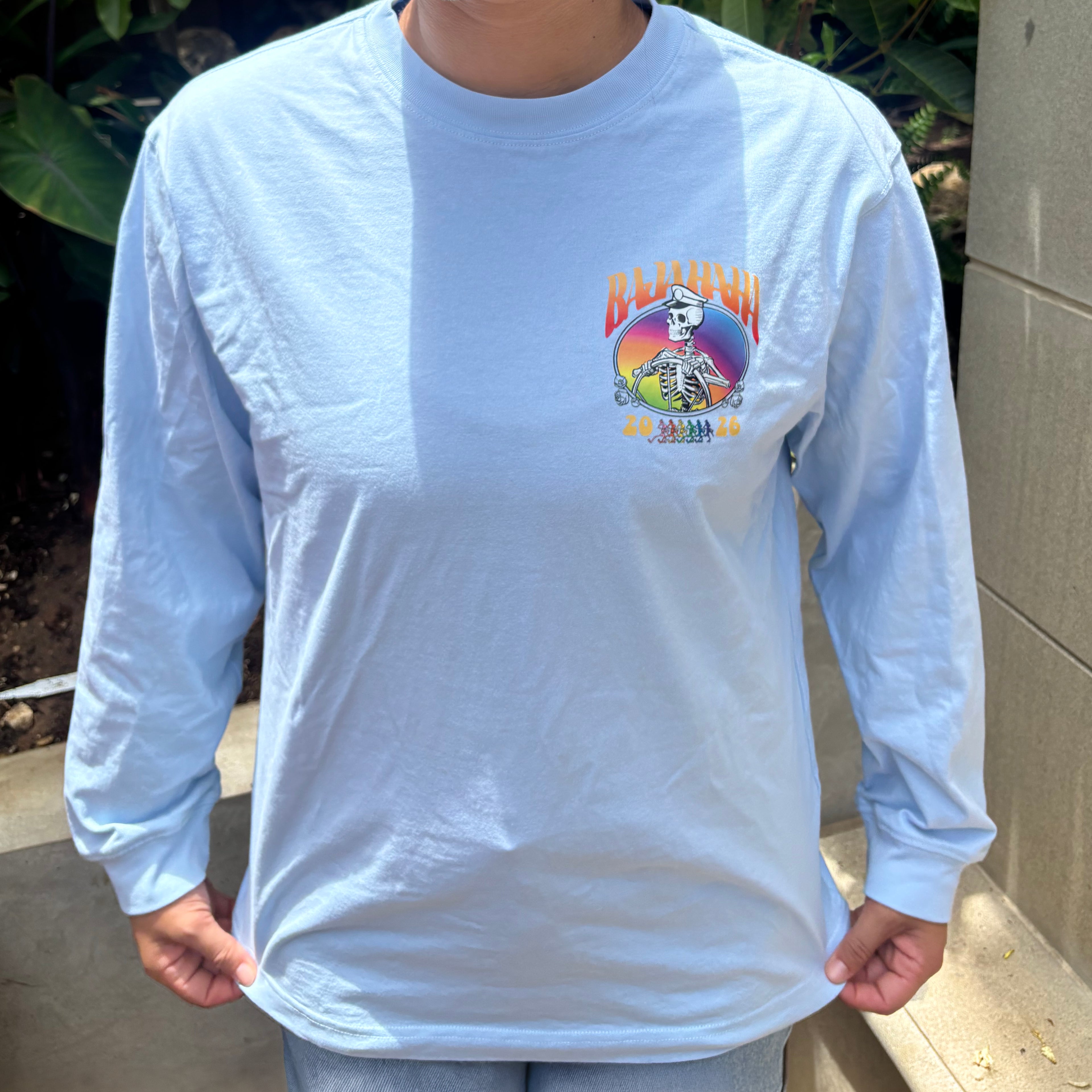 The front of a grey shirt with a skeleton captain and the words Baja Haha 2026 on the front left. There is a sunset background to the skeleton.